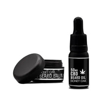 Load image into Gallery viewer, An open jar of NKD Honey Oak Beard Oil balm and a small bottle of 150mg CBD Honey Oak beard oil are displayed against a white background. Both items, part of the luxurious NKD CBD-infused gift set for beard care, feature black packaging with white text and cannabis leaf graphics.
